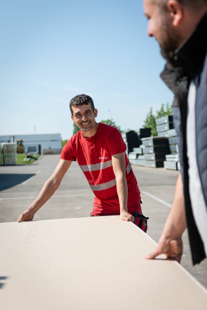 Un vendeur qui aide un client à transporter une plaque de placo