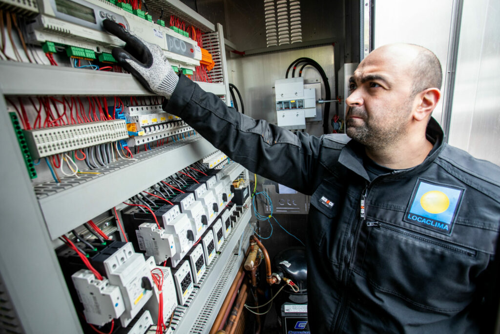 Un électricien devant un tableau électrique en train de faire de la maintenance.