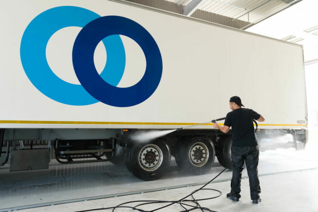 Personne qui nettoie au karcher une remorque de camion Stef