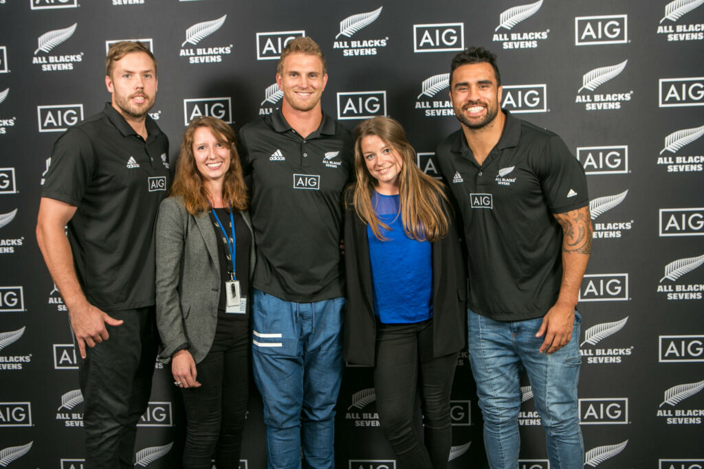 Deux femmes qui posent avec trois rugbyman connus devant un photocall AIG