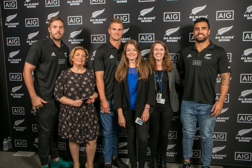 Trois femmes qui posent avec trois rugbyman connus devant un photocall AIG