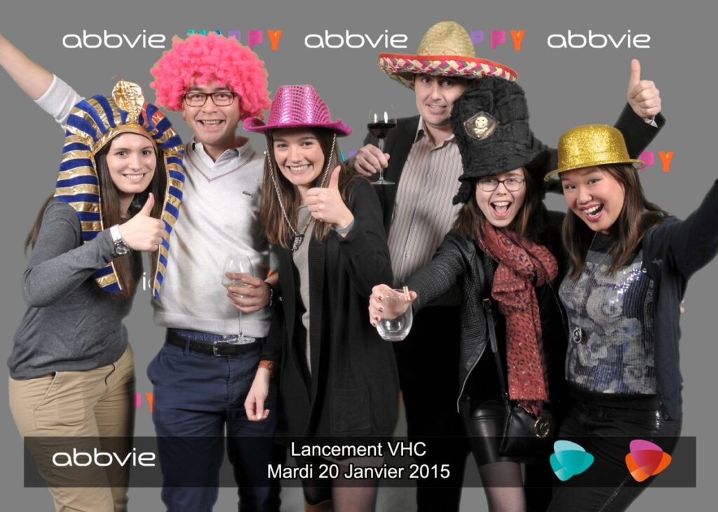 6 personnes déguisées avec des chapeaux colorés et rigolos posant pour un photocall de abbvie.