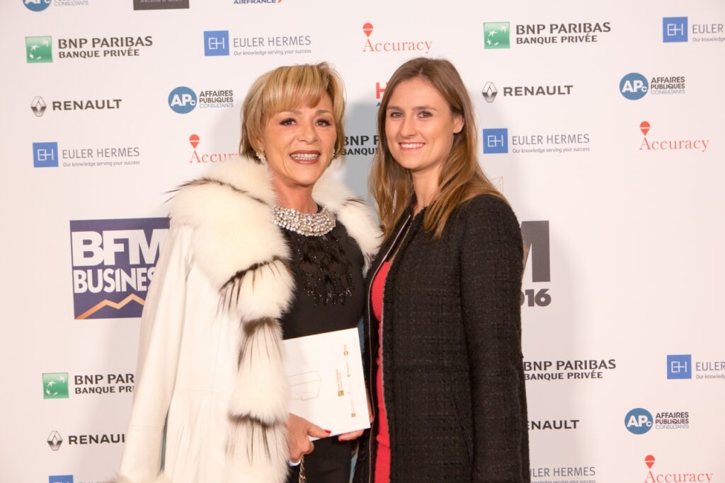 Deux femmes qui posent devant un photocall pour un evenement BFM Business