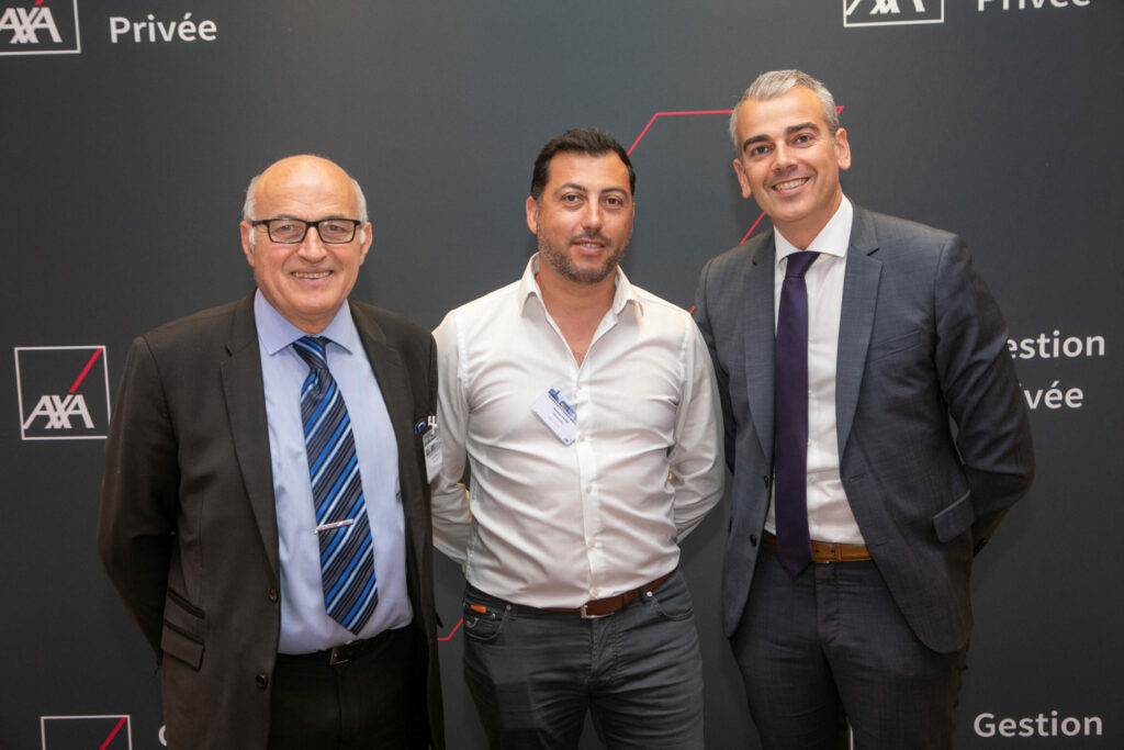 Trois hommes qui prennent la pose devant un photocall AXA