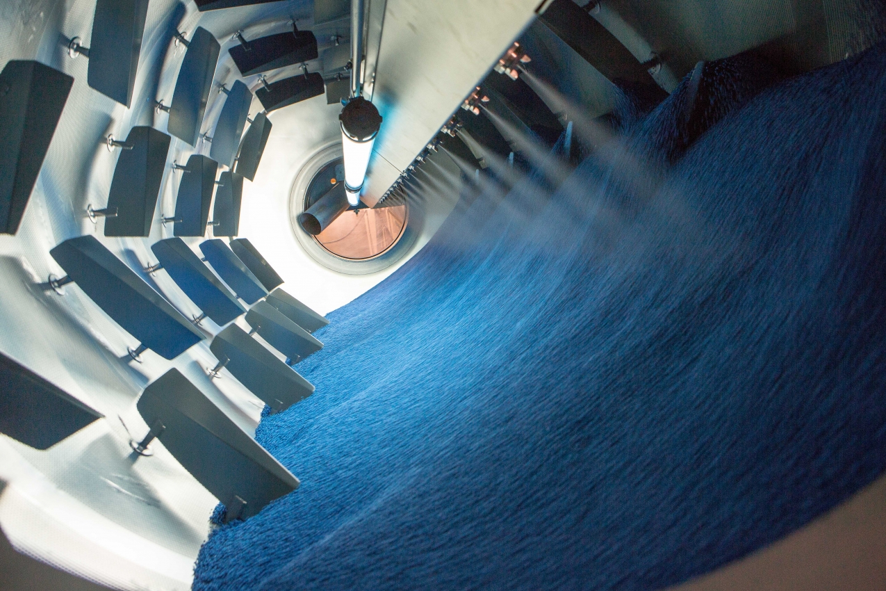 Des graines sont pulvérisées d'un produit colorant bleu, dans un centrifugeur industriel.