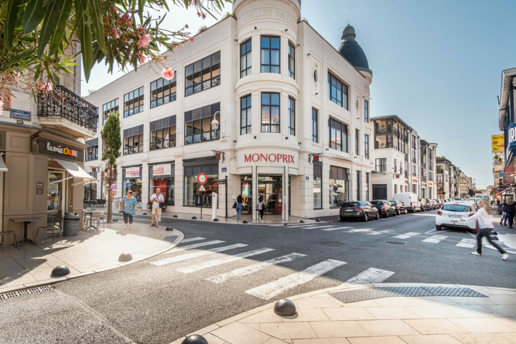 Une devanture de supermarché Monoprix. Prise de vue grand angle, laissant apercevoir une intersection de deux rues.