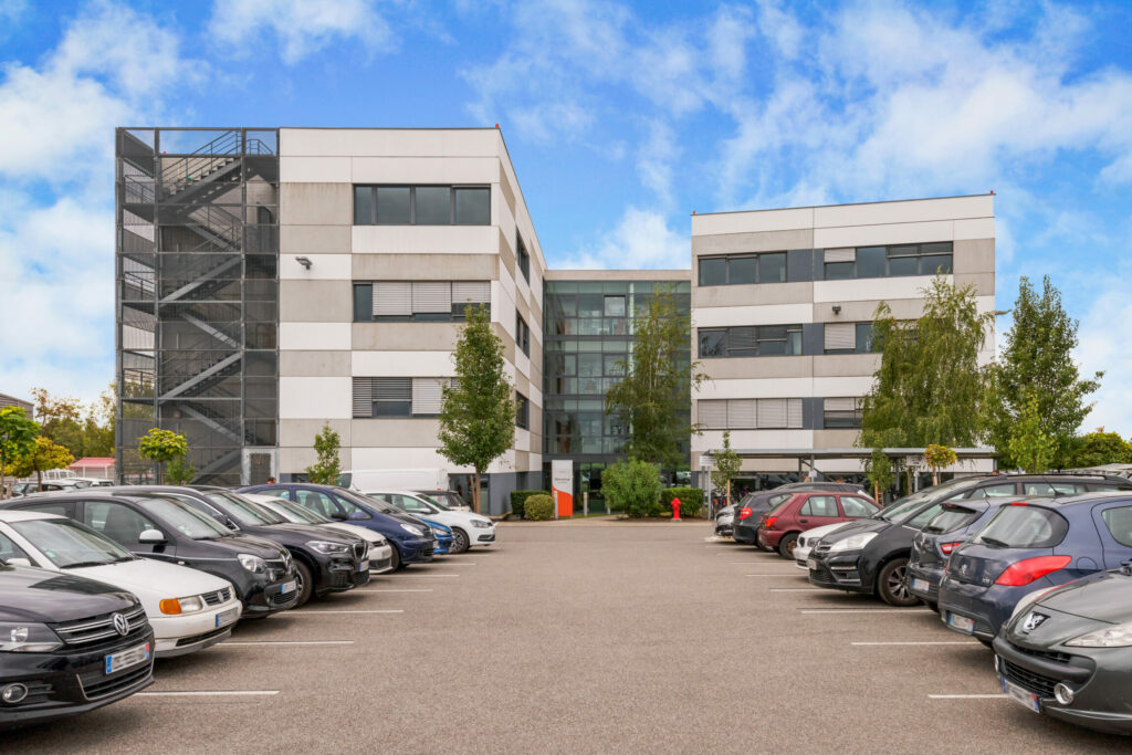 Immeuble moderne en fond de l'image, avec un deux rangées de voitures sur un parking.