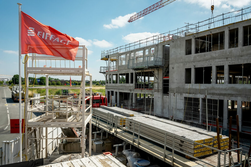 Un chantier d'immeuble en construction avec des matériaux et un drapeau Eiffage.