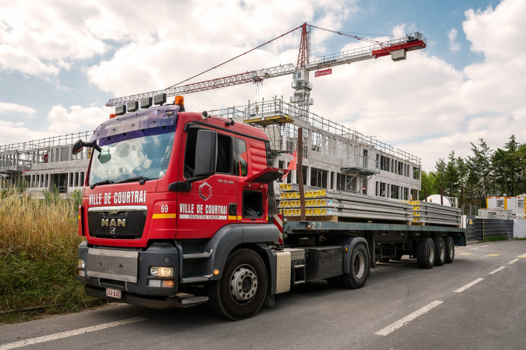 Photo d'un camion qui livre du matériel sur le chantier d'un bâtiment en construction