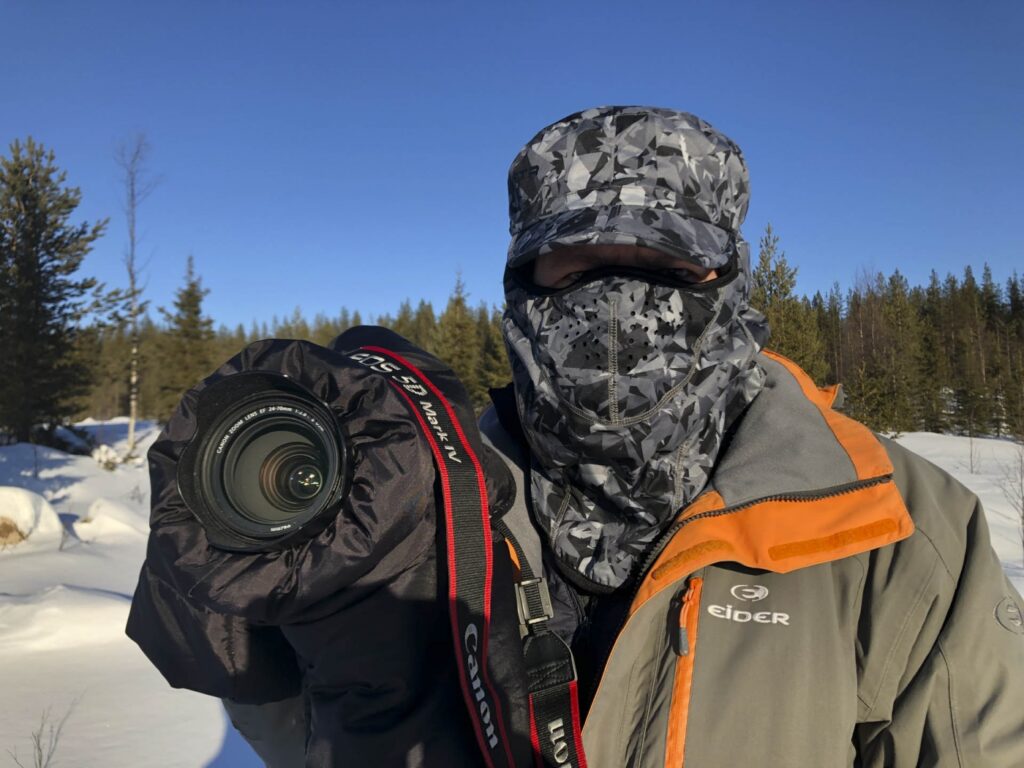 Un photographe avec son matériel équipé pour affronter des températures basses dans une forêt enneigée