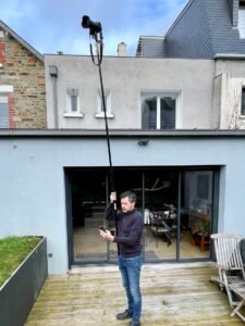 Un photographe dans un jardin qui utilise une perche à appareil photo.