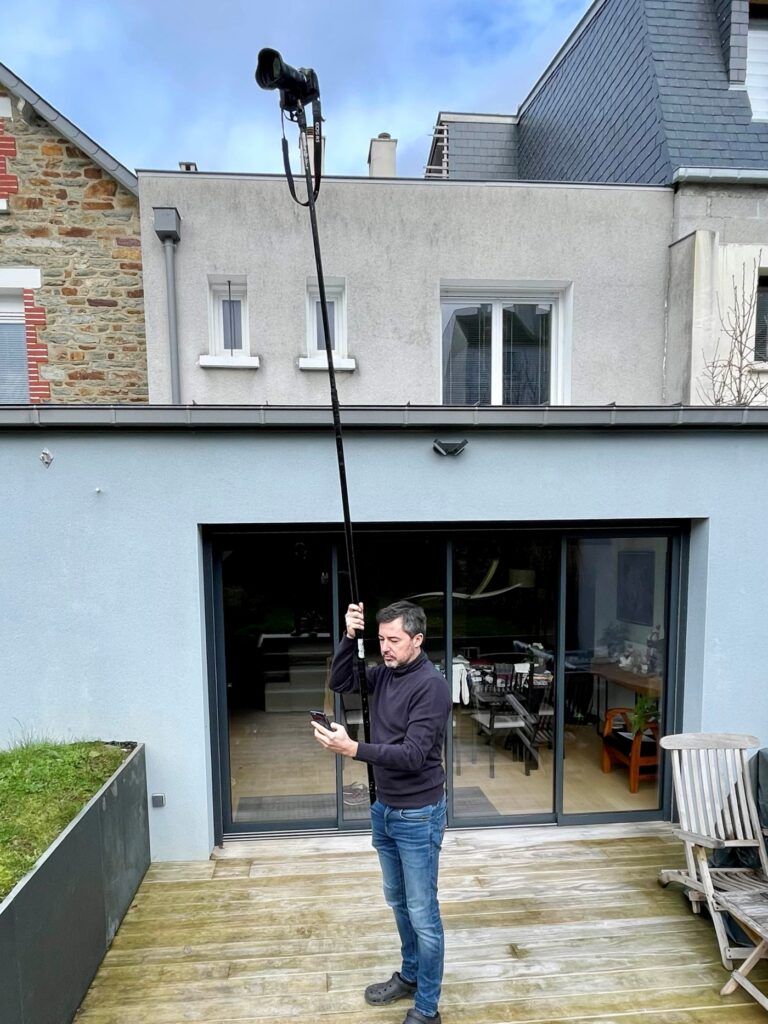 Un photographe dans un jardin qui utilise une perche à appareil photo.