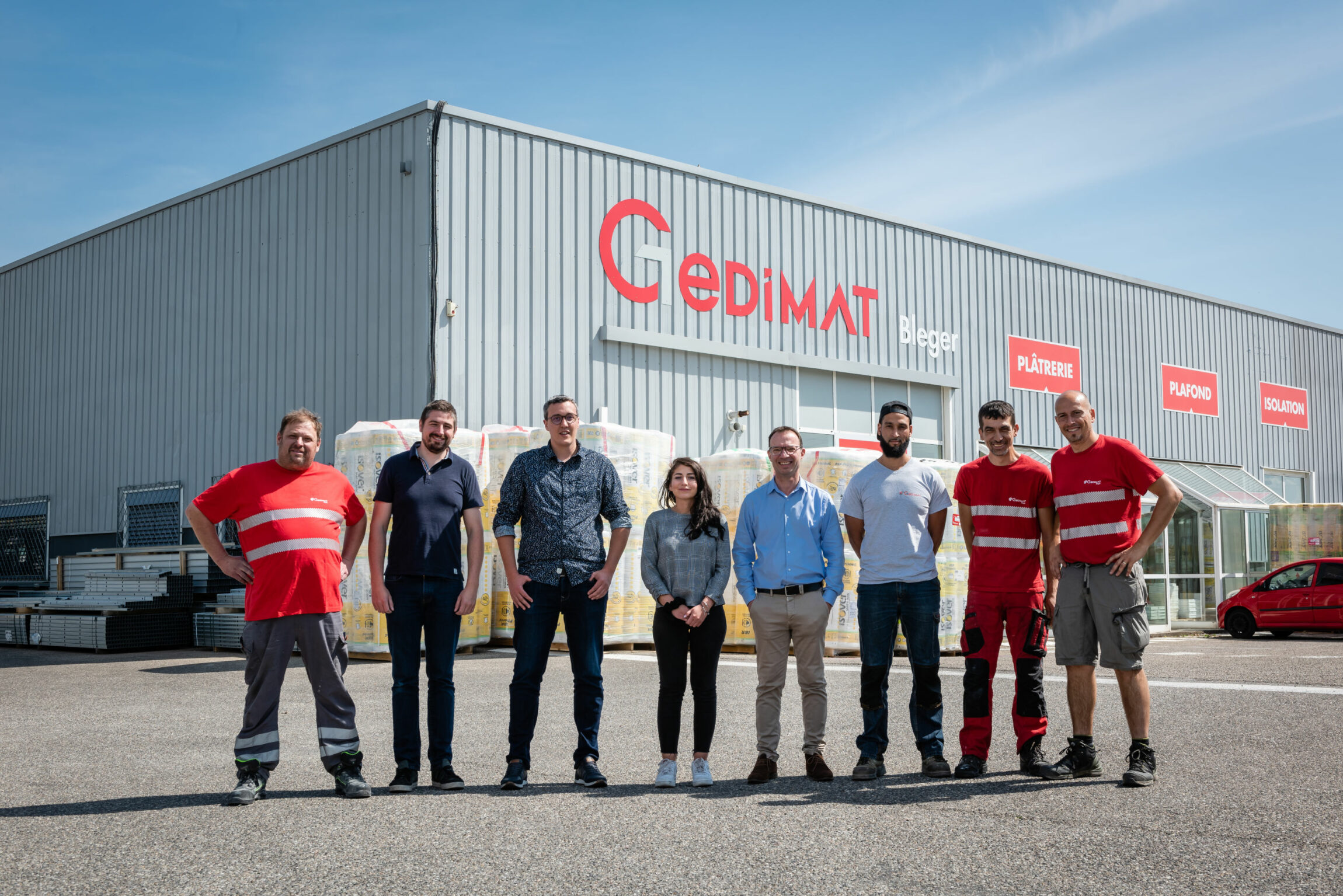 Portrait d'un groupe de collaborateurs devant l'enseigne Gedimat.