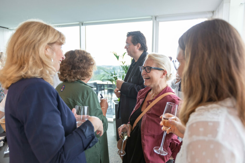 Un groupe de personne discute avec des flutes de champagnes à la main.