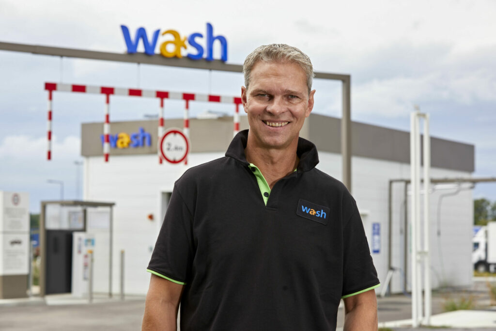 Portrait d'un collaborateur Total posant devant une station de lavage Total